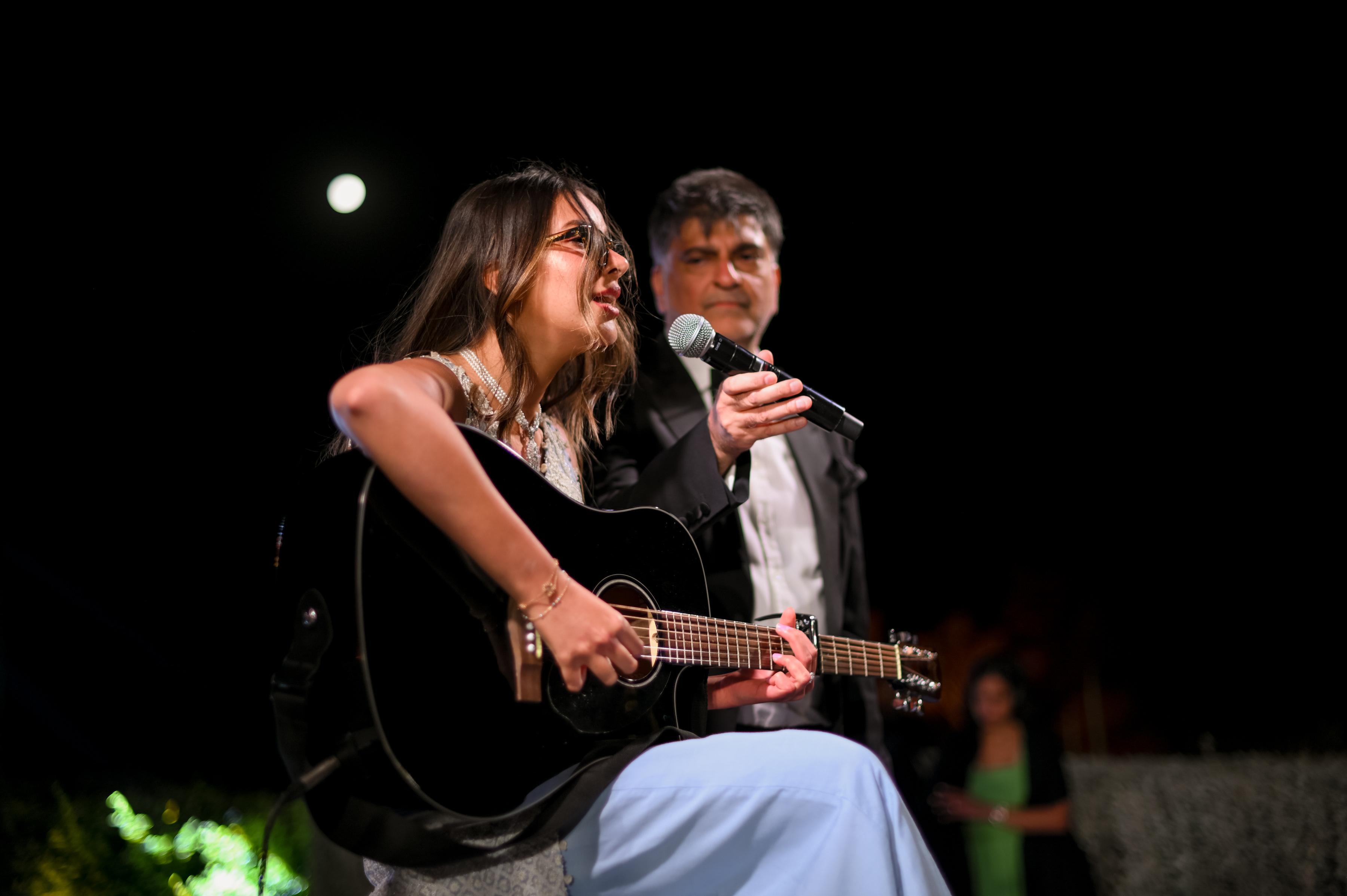 Singer in soft spotlight on a dimly lit stage.